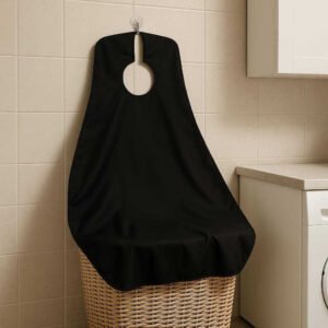 Barberingsforklæde med Sugekopper til Effektiv Hårfangst - Høj Kvalitet og Nem Oprydning: A different realistic home setting in a laundry room, where the barbering cape is neatly hung up on a hook using its suction cups after use.