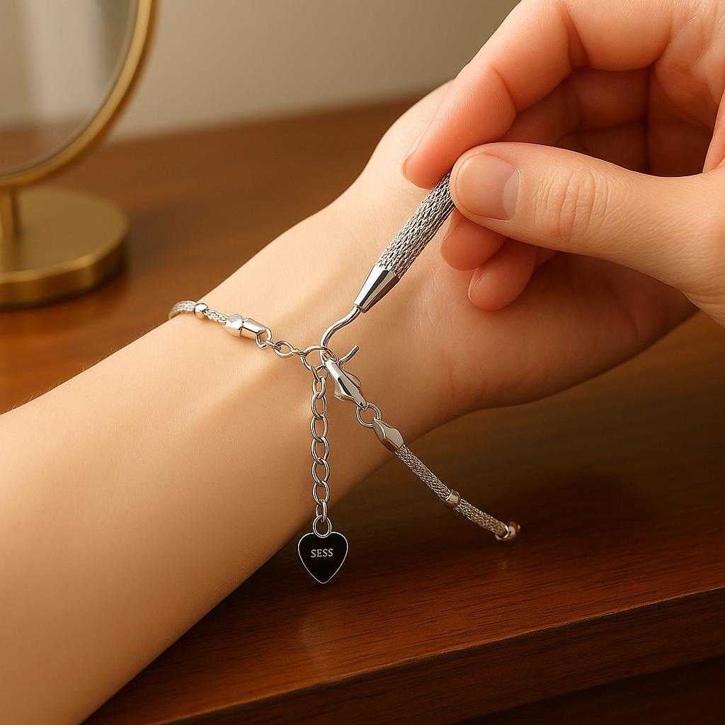 armbnd-vrktj-i-metal-metal-og-plastik-gylden-sl_15378295095683_scene1 Armbånd værktøj i 'metal' = 'metal' og plastik - Gylden, Sølvfarvet, Rosa Gylden - God kvalitet: A realistic dressing table setting where the bracelet tool is properly grounded on the glossy wooden surface, being actively used by a person adjusting a bracelet on their wrist.