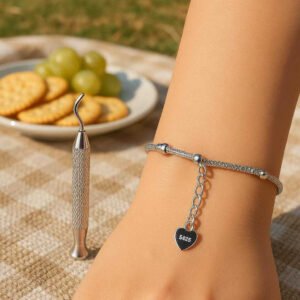 Armbånd værktøj i 'metal' = 'metal' og plastik - Gylden, Sølvfarvet, Rosa Gylden - God kvalitet: A different realistic outdoor picnic setting where the bracelet tool is securely positioned on a picnic blanket alongside a plate of snacks.