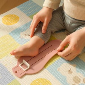 Fodmåler til børn - Præcis og nem måling af fodstørrelse i hjemmet - Tilgængelig i lyserød, blå og grøn: A realistic nursery setting where the product is properly grounded on a soft, colorful baby mat, being actively used by a caregiver measuring a toddler's foot.