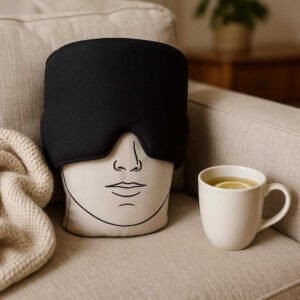 Migrænehat med kølende effekt - Bedste migrænehatten til bedre søvnkvalitet og lindring af hovedpine: A different realistic living room setting where the Migraine Hat is securely positioned on a soft couch, being naturally placed beside a cozy blanket and a cup of herbal tea, suggesting an inviting environment for relaxation, with proper physics, shadows, and realistic integration into the environment.