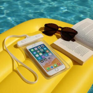 Mobilpose - Vandtæt og Touch-venlig, Perfekt til Svømning & Strand, Tilgængelig i 8 Farver: A different realistic pool setting where the waterproof phone pouch is securely positioned on a pool float, naturally placed next to a pair of sunglasses and a book.