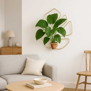 Planteholdere i Messing til Væg - Eksklusiv Dekoration til Hjemmet i Skandinavisk Stil. The elegant brass wall-mounted plant holder is showcased in a chic Scandinavian living room, holding a lush green plant against a white wall with minimalist furniture in the background.