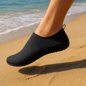 Strandsokker tilbehør - Skridsikre badesokker til strand og vandaktiviteter: A realistic beach setting where the sock is properly grounded on warm sand, being actively used by a person walking along the shoreline.